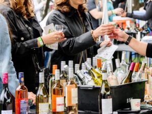 wine bottles, glasses and people drinking at lincoln park wine fest