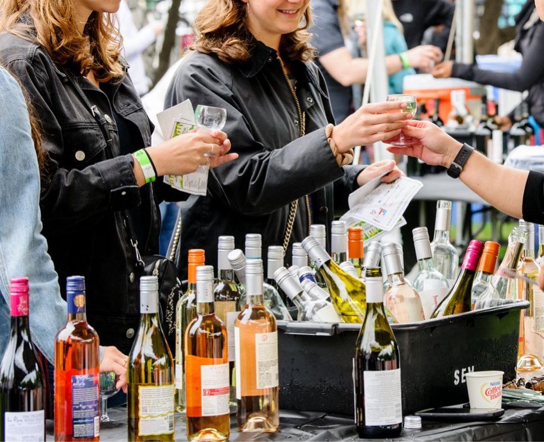 wine bottles, glasses and people drinking at lincoln park wine fest